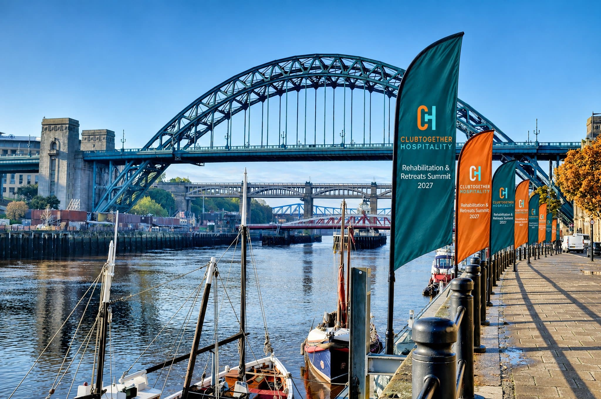 A row of summit flags along the Quayside promenade beneath the Tyne Bridge on a sunny morning